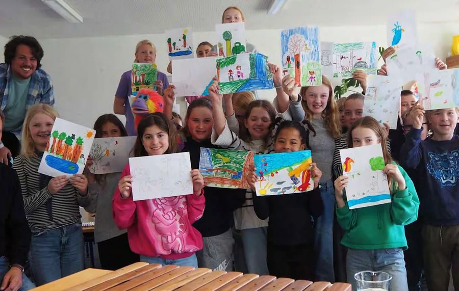 Pupils at Bjerregrav Friskole holding up their rainforest drawings, a marimba in front